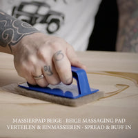 Beiges Massierpad mit Hand-Padhalter zum Verteilen und Einmassieren von Holzöl auf einer Holzoberfläche.